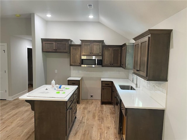2101 N 31st Ter, Saint Joseph, MO 64506 - kitchen with stainless steel microwave, dark brown cabinets, lofted ceiling, light wood-style flooring, and a center island