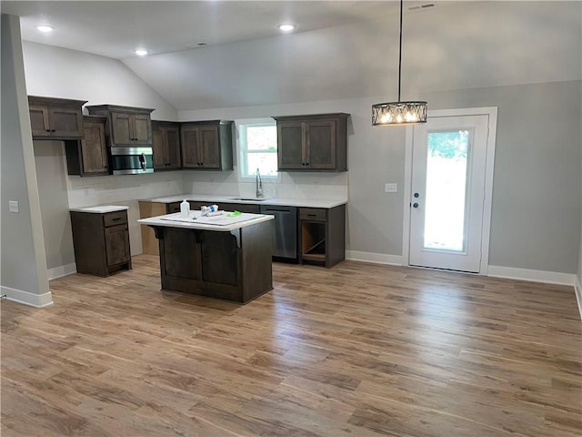 2101 N 31st Ter, Saint Joseph, MO 64506 - kitchen featuring appliances with stainless steel finishes, vaulted ceiling, dark brown cabinets, light wood-style floors, and a center island