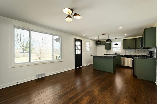 kitchen with visible vents, dark wood-type flooring, dark countertops, decorative backsplash, and dishwasher