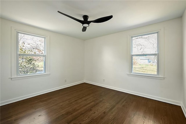 spare room with dark wood-style floors, a ceiling fan, and baseboards