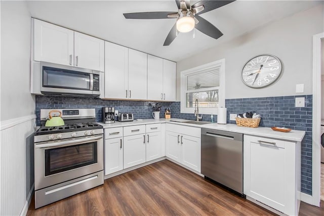 kitchen with a sink, stainless steel appliances, dark wood finished floors, and light countertops