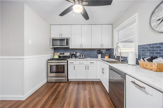 kitchen featuring dark wood finished floors, ceiling fan, a sink, appliances with stainless steel finishes, and white cabinetry