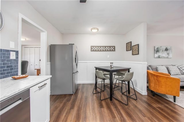 kitchen with light stone countertops, dark wood-style flooring, and stainless steel appliances