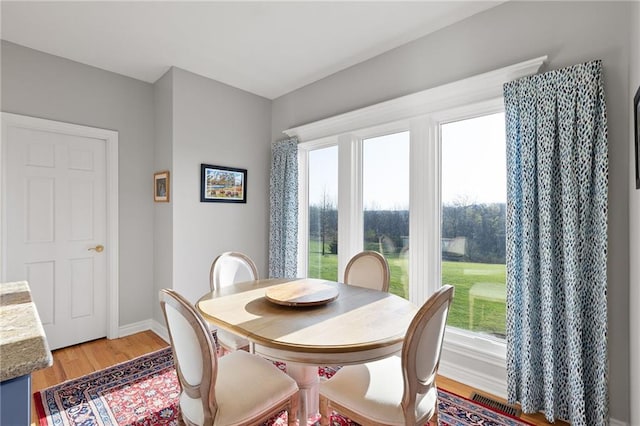 dining space with a wealth of natural light, light wood-style floors, and baseboards