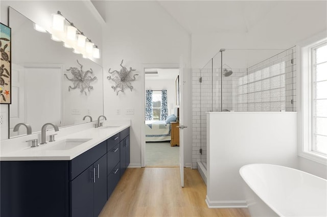 ensuite bathroom featuring wood finished floors, a tile shower, and a sink