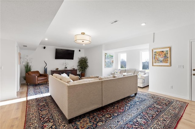 living area featuring visible vents, light wood finished floors, and recessed lighting