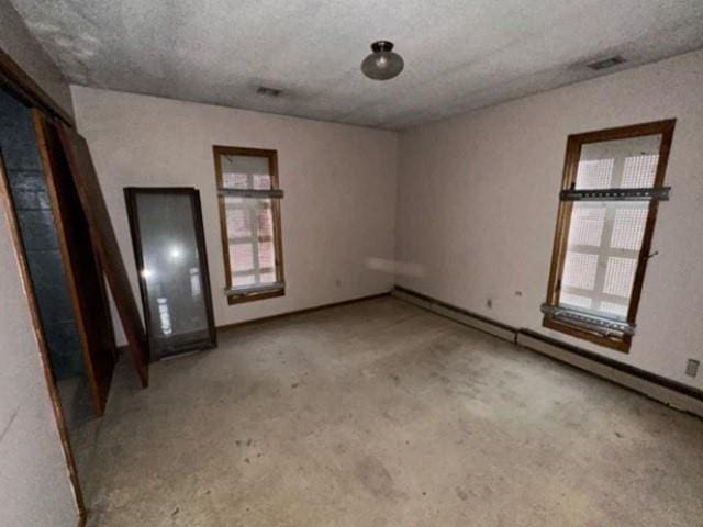 empty room with visible vents, plenty of natural light, and a textured ceiling