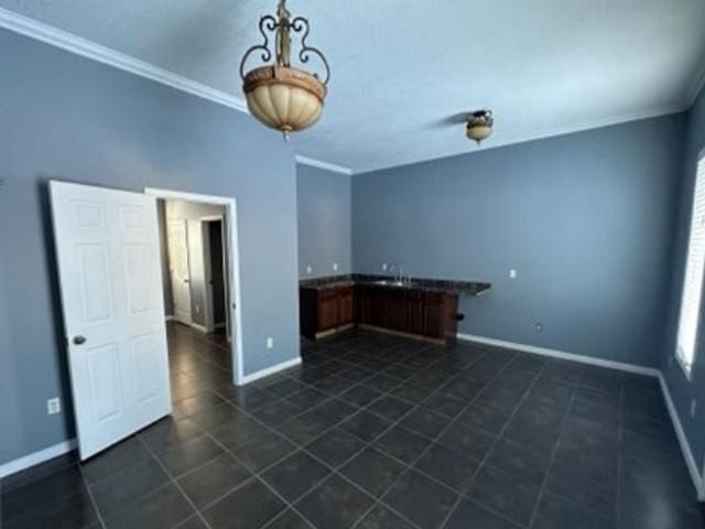 unfurnished room featuring dark tile patterned floors, baseboards, and ornamental molding