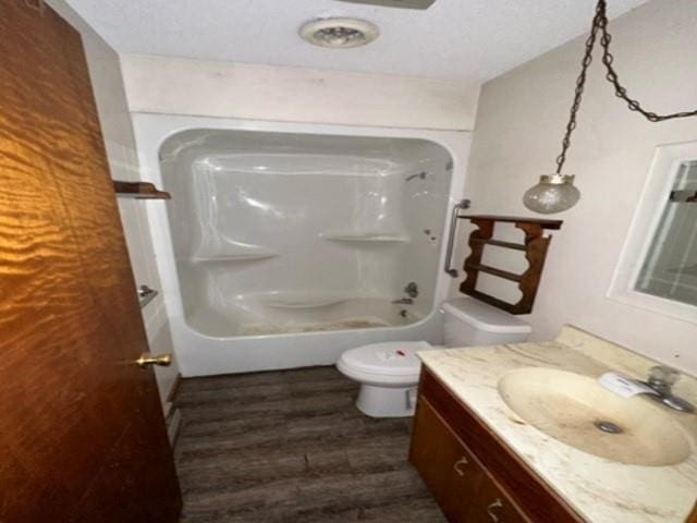 bathroom with vanity, toilet, wood finished floors, and tub / shower combination