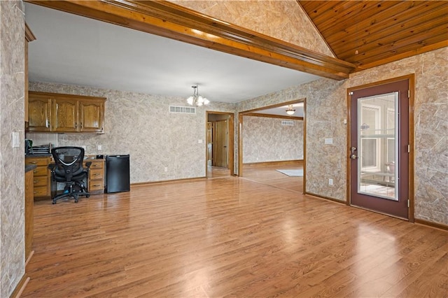 unfurnished living room featuring visible vents, light wood finished floors, baseboards, a chandelier, and vaulted ceiling