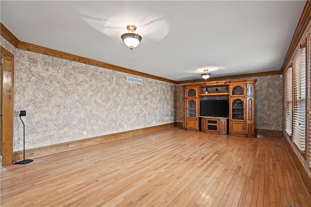 unfurnished living room featuring crown molding, hardwood / wood-style flooring, baseboards, and visible vents