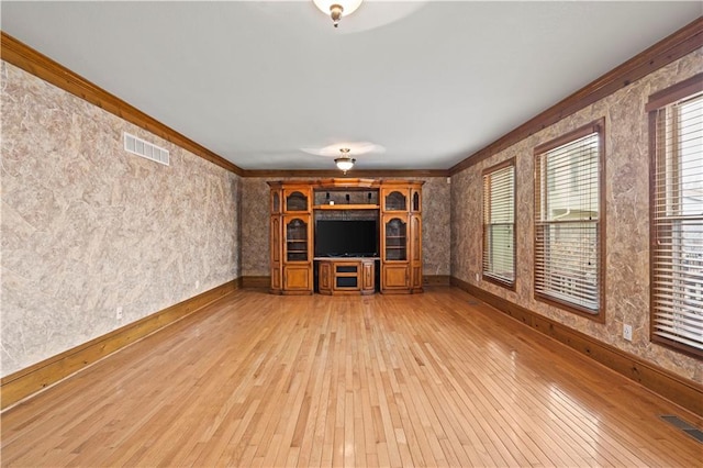 unfurnished living room with crown molding, light wood-style flooring, baseboards, and visible vents