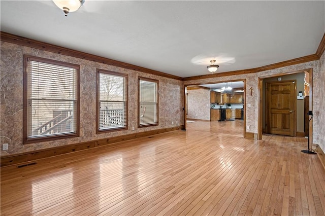 unfurnished living room with visible vents, crown molding, baseboards, light wood-style floors, and a notable chandelier