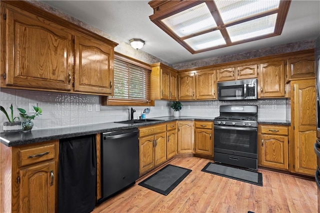 kitchen featuring stainless steel microwave, dishwasher, brown cabinetry, gas stove, and a sink