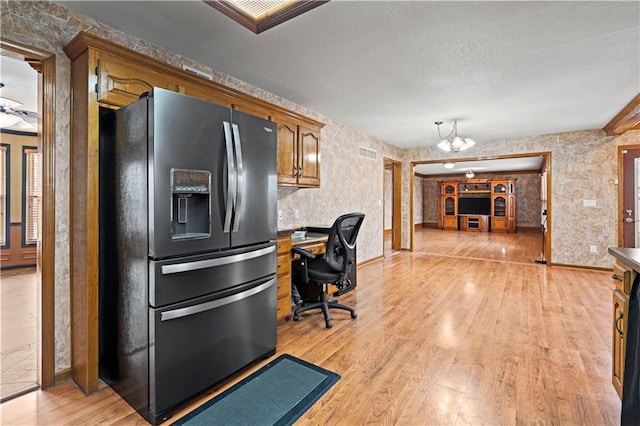 kitchen with visible vents, light wood-style flooring, a textured ceiling, stainless steel fridge, and a chandelier