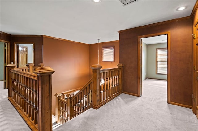 hallway with visible vents, an upstairs landing, baseboards, and carpet flooring