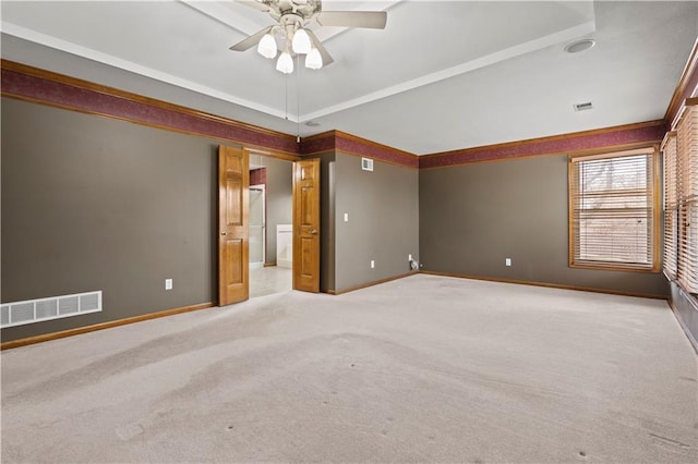 carpeted empty room featuring ornamental molding, baseboards, visible vents, and ceiling fan