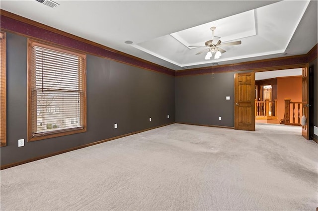 interior space featuring visible vents, baseboards, a tray ceiling, crown molding, and carpet flooring