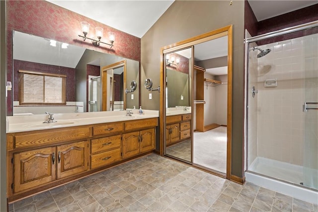 bathroom featuring double vanity, a stall shower, a sink, and vaulted ceiling