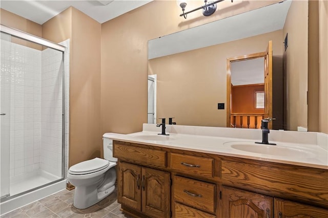 bathroom featuring double vanity, a stall shower, toilet, and a sink