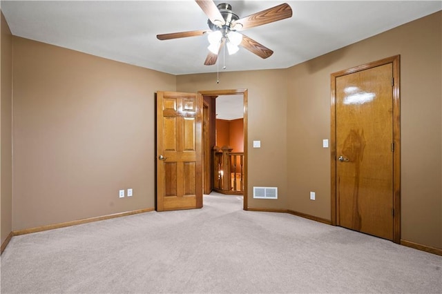 unfurnished bedroom featuring visible vents, light colored carpet, a ceiling fan, and baseboards