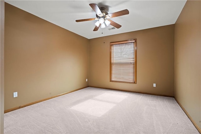 spare room featuring ceiling fan, baseboards, visible vents, and light carpet