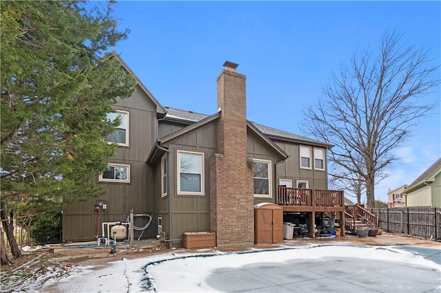 rear view of house with a chimney, stairs, a deck, and fence