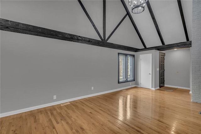 unfurnished room featuring beamed ceiling, high vaulted ceiling, a notable chandelier, light wood-style flooring, and baseboards