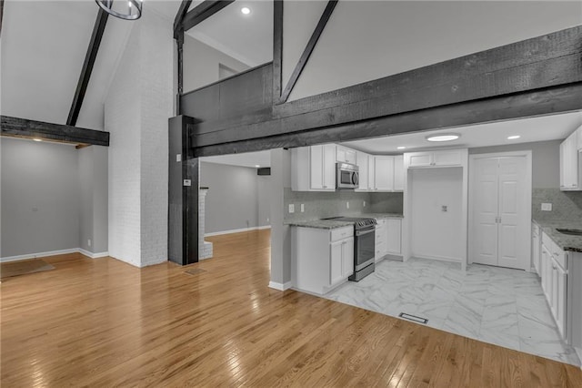 kitchen featuring stainless steel microwave, beamed ceiling, white cabinetry, and electric stove