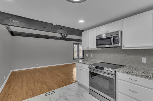 kitchen featuring light stone counters, baseboards, appliances with stainless steel finishes, white cabinetry, and tasteful backsplash