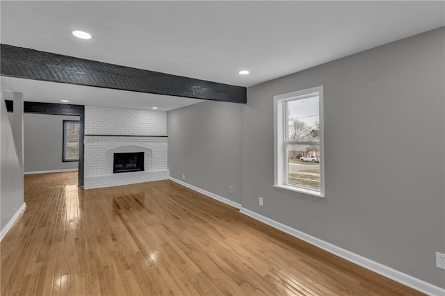 unfurnished living room with a brick fireplace, light wood-style flooring, recessed lighting, and baseboards