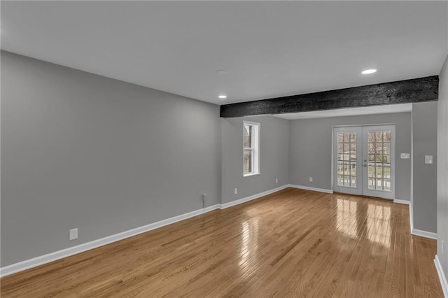 empty room featuring beam ceiling, french doors, baseboards, and wood finished floors