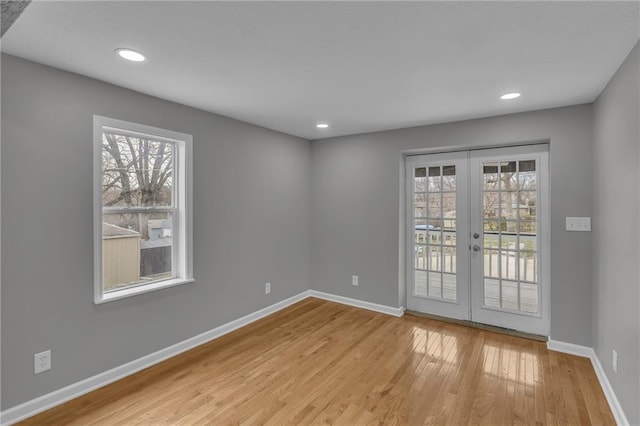 spare room with french doors, plenty of natural light, baseboards, and light wood finished floors