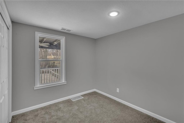 carpeted empty room with visible vents and baseboards