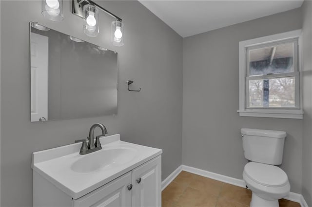 half bathroom with tile patterned flooring, toilet, vanity, and baseboards