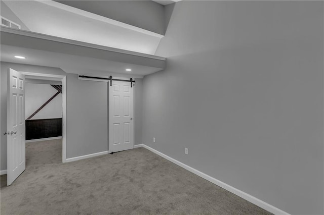 below grade area featuring a barn door, carpet floors, baseboards, and visible vents