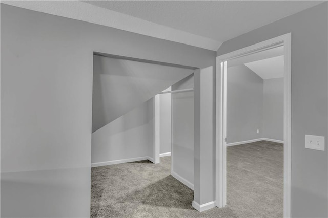 additional living space with vaulted ceiling, carpet, baseboards, and a textured ceiling