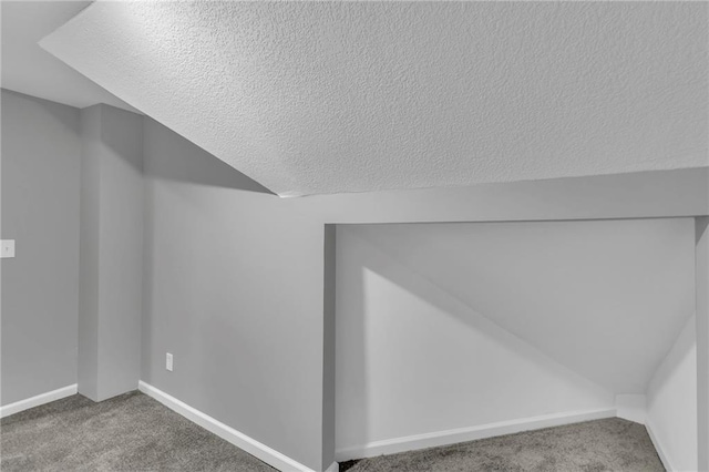 bonus room featuring vaulted ceiling, carpet, baseboards, and a textured ceiling