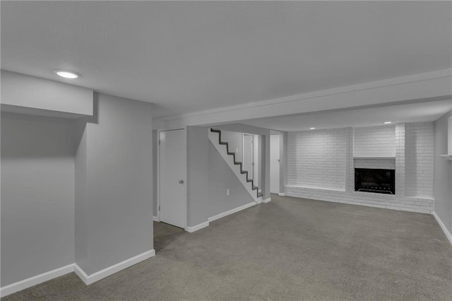 finished basement featuring stairs, baseboards, a brick fireplace, and carpet flooring