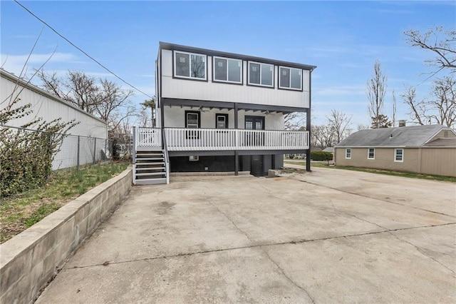 rear view of property with covered porch, concrete driveway, and fence