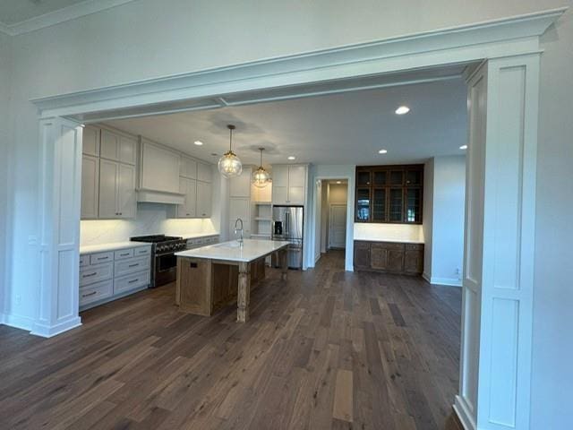 kitchen with light countertops, custom exhaust hood, appliances with stainless steel finishes, dark wood-style floors, and a sink