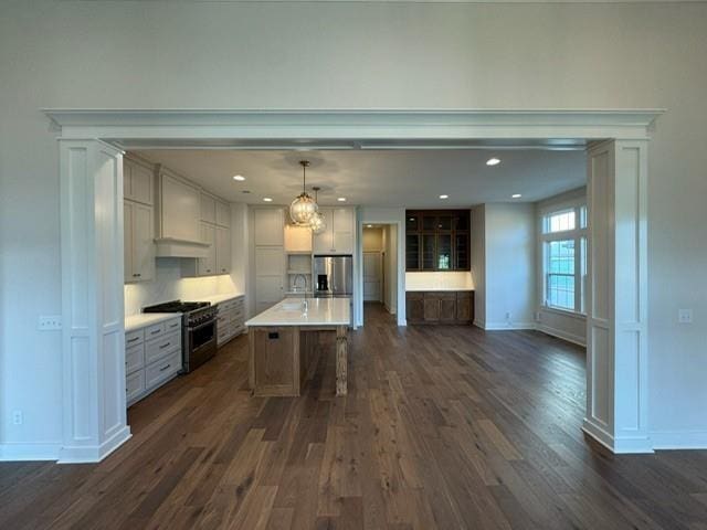 kitchen featuring dark wood-style flooring, appliances with stainless steel finishes, a breakfast bar area, and premium range hood