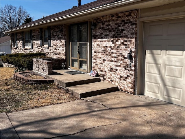 property entrance featuring brick siding, driveway, and a garage