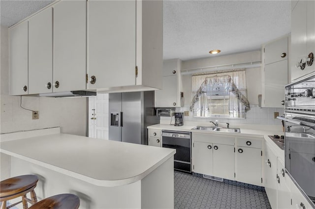 kitchen featuring light countertops, black dishwasher, decorative backsplash, a textured ceiling, and a sink