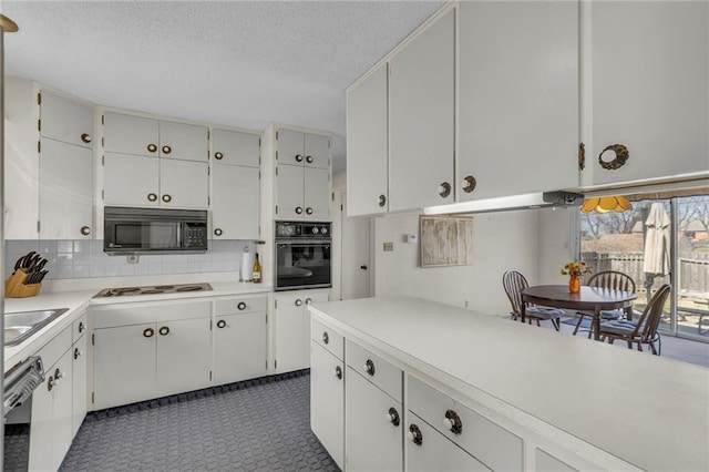 kitchen featuring backsplash, black appliances, light countertops, white cabinets, and a textured ceiling