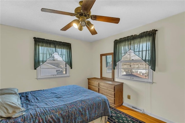 bedroom with ceiling fan, visible vents, baseboards, and wood finished floors