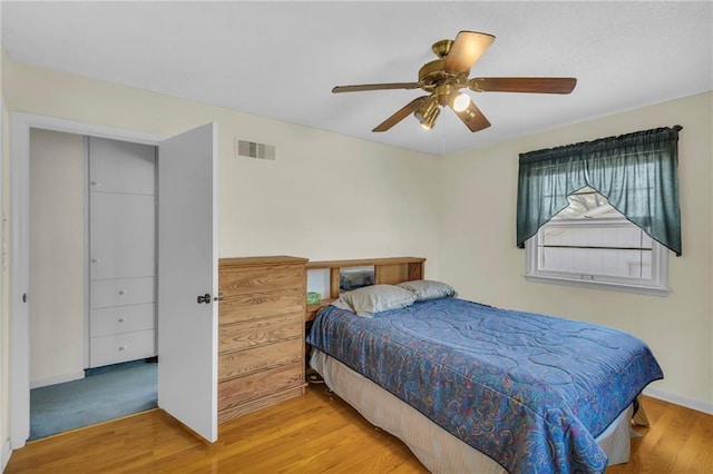 bedroom featuring ceiling fan, visible vents, baseboards, and wood finished floors