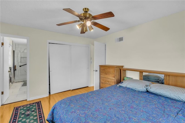 bedroom featuring visible vents, ceiling fan, ensuite bathroom, wood finished floors, and a closet