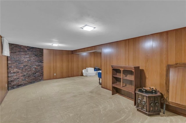 finished basement featuring wood walls, brick wall, and light floors