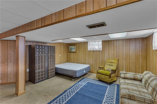 bedroom with concrete floors, visible vents, and wood walls